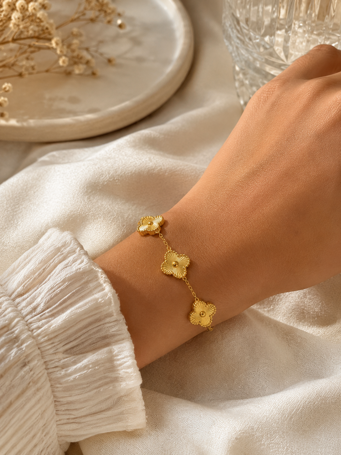 Gold bracelet with floral designs on a wrist, set against a neutral background.