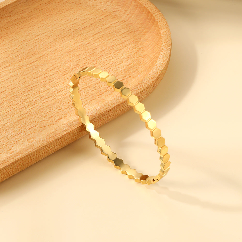 Gold hexagonal band ring on a wooden surface
