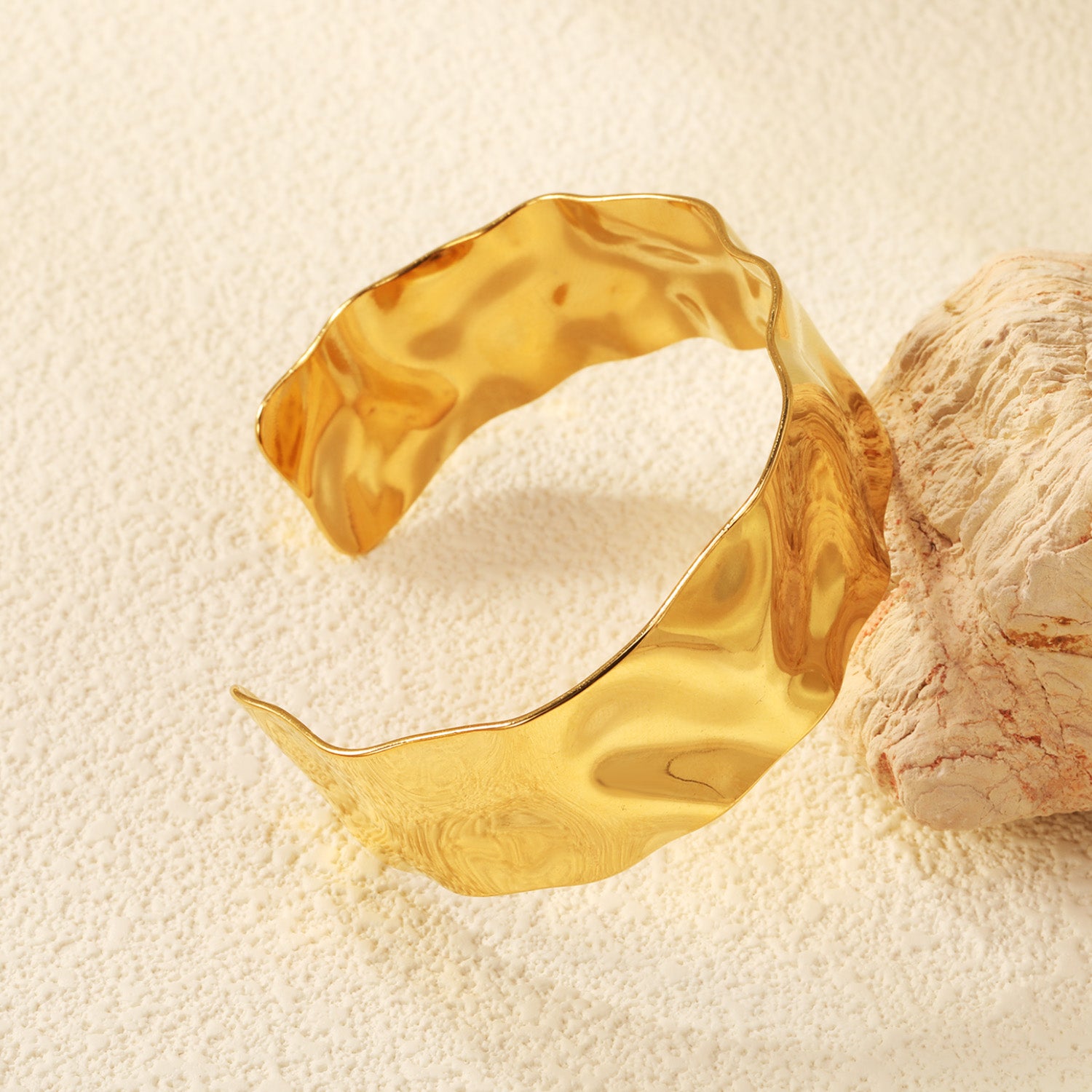 Gold bracelet on a textured beige surface