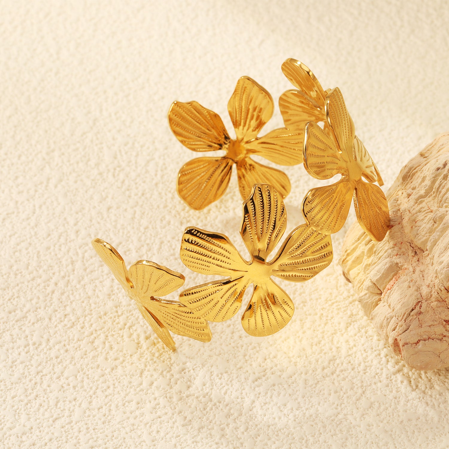 Gold butterfly-shaped jewelry on a textured beige surface