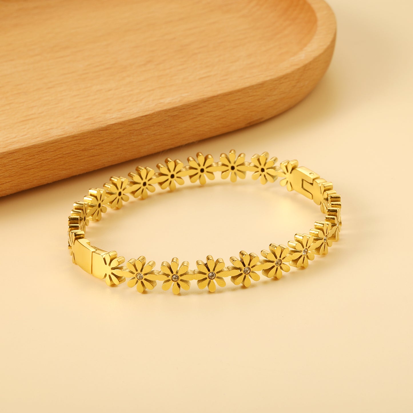 Gold bracelet with floral designs on a beige background