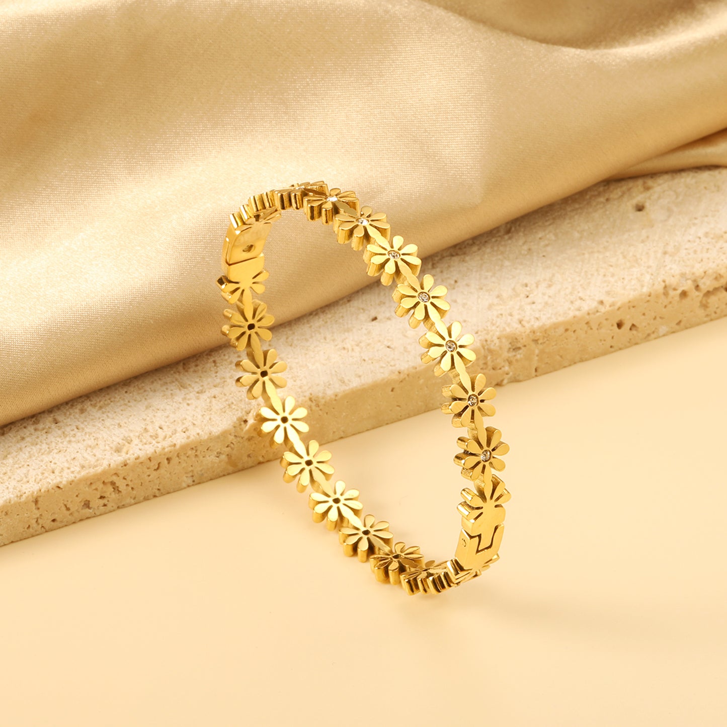 Gold bracelet with floral designs on a beige fabric background
