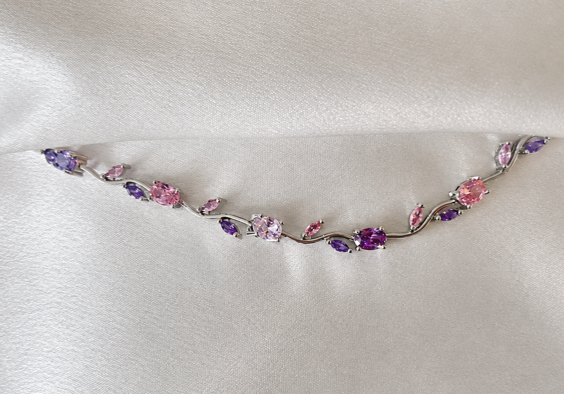 Delicate silver necklace with multicolored gemstones on a white fabric background