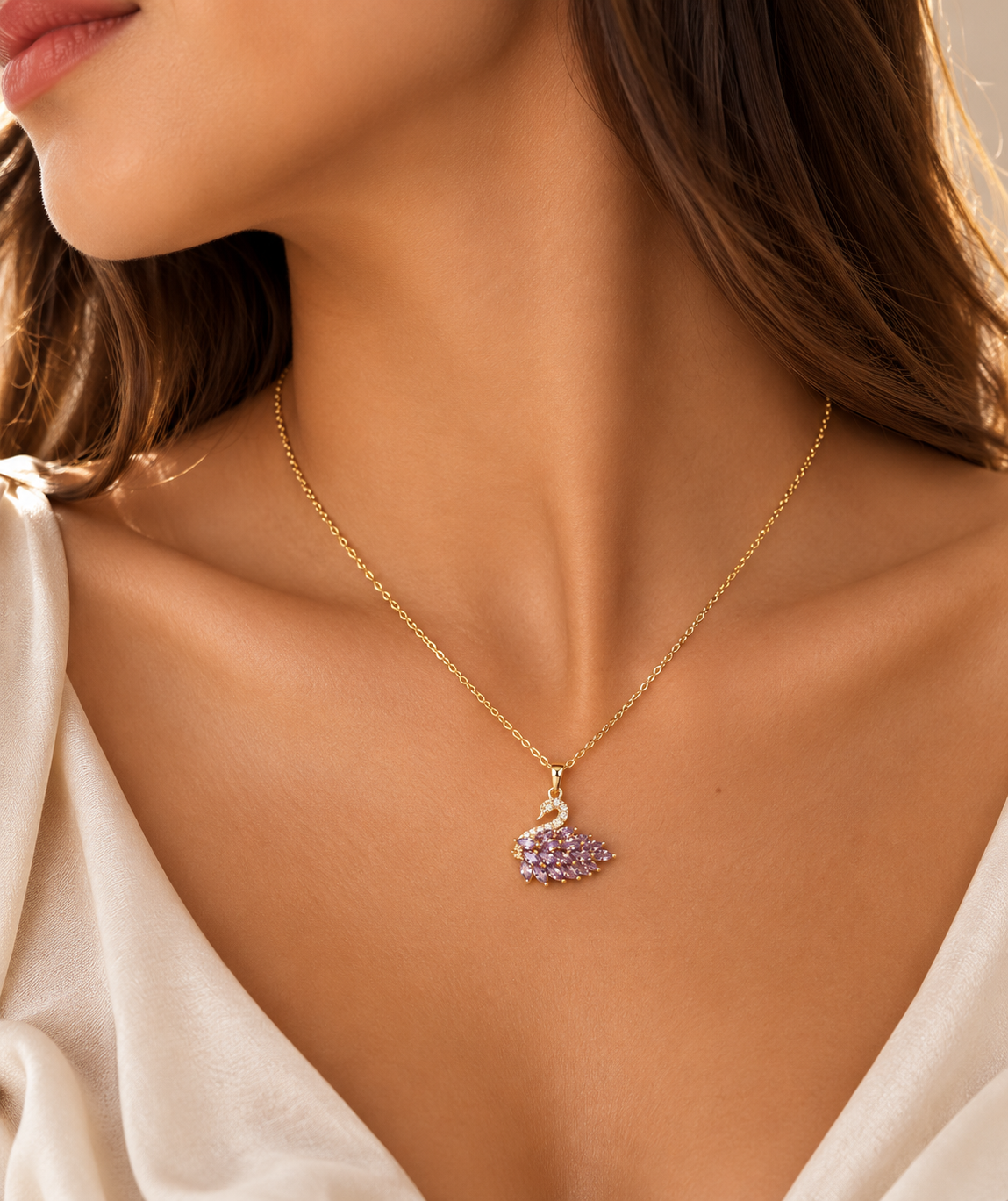 A close-up lifestyle shot of a model wearing a delicate gold chain necklace with a small pendant paved with light purple stones.