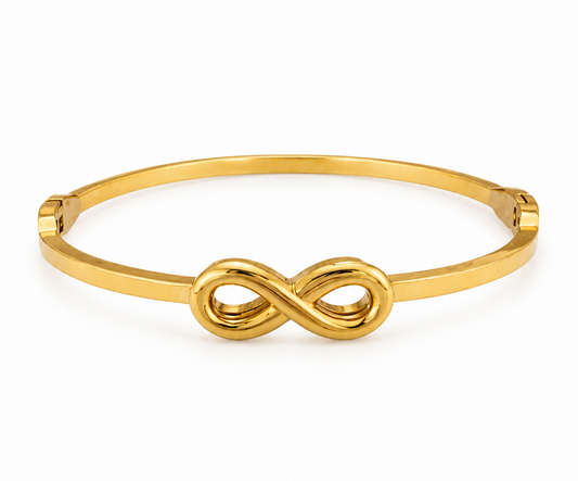 A polished gold bangle bracelet featuring a central infinity symbol, set against a clean white background.