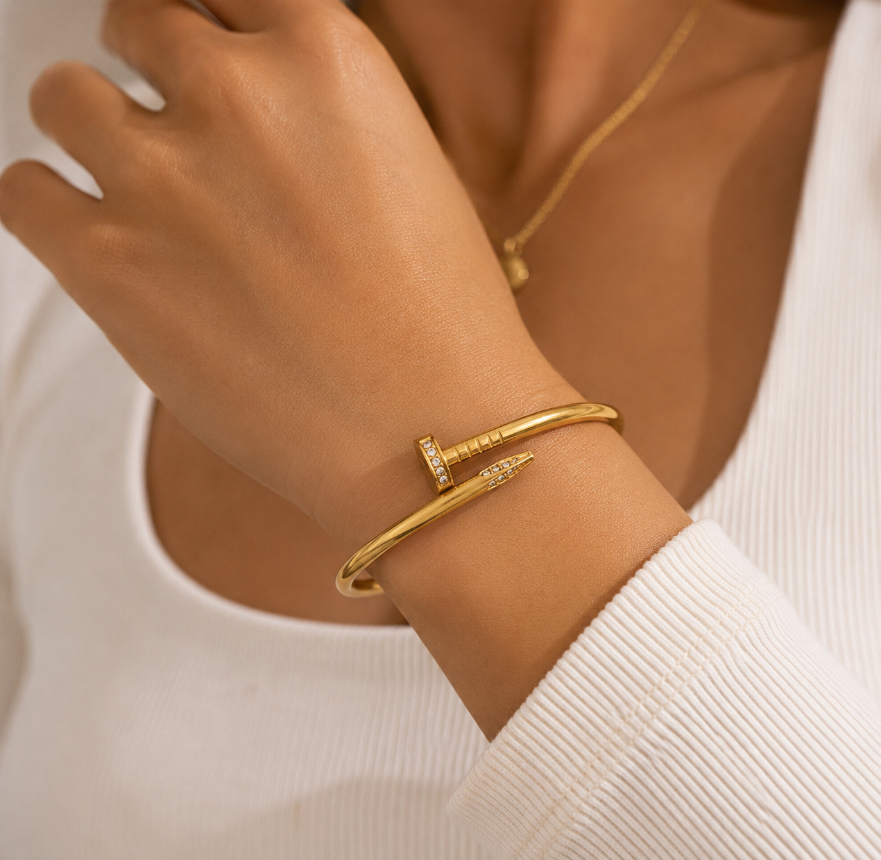 Gold bracelet on a wrist with a neutral background