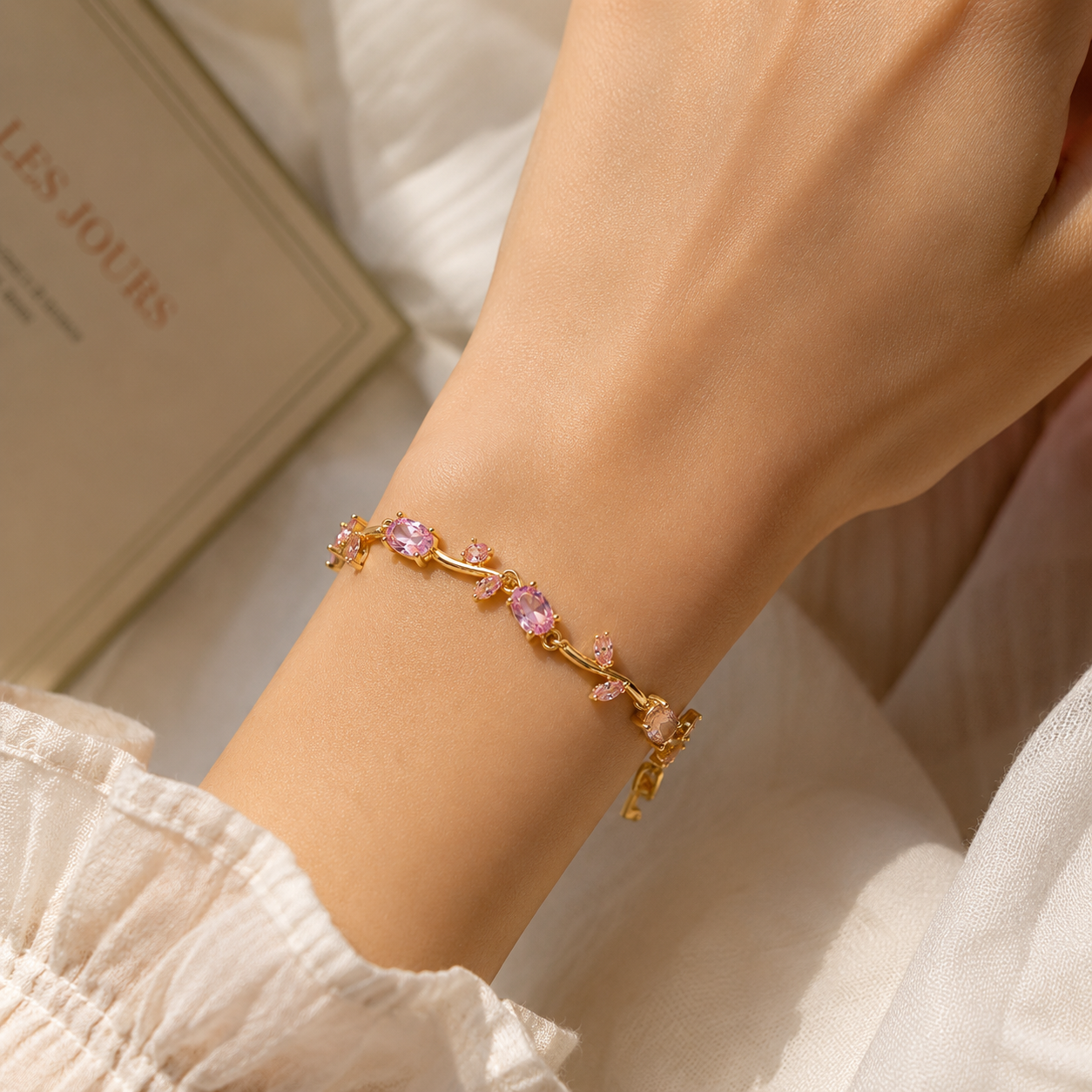Gold bracelet with pink stones on a wrist, blurred background