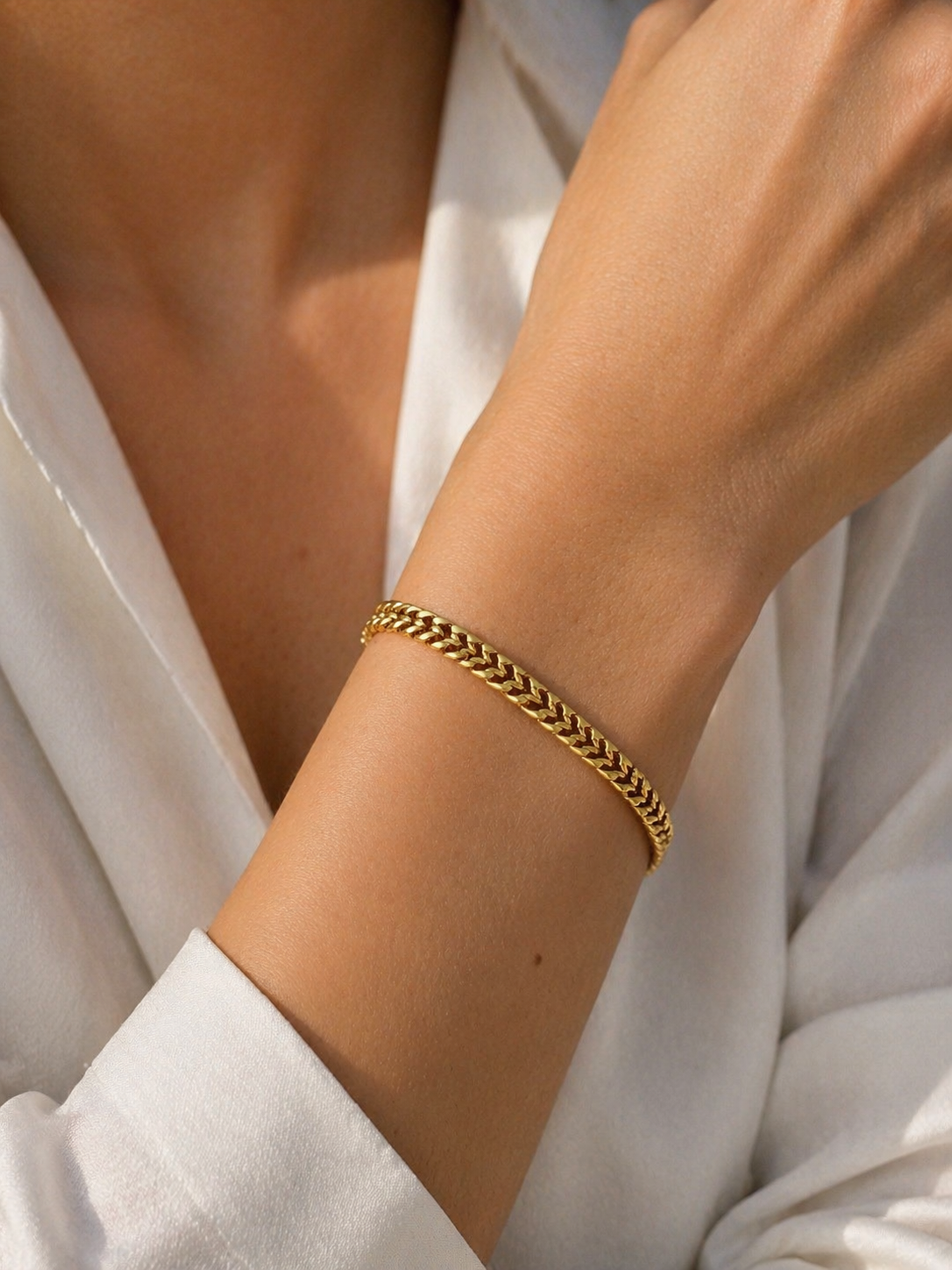 Gold chain bracelet on a person wearing a white shirt