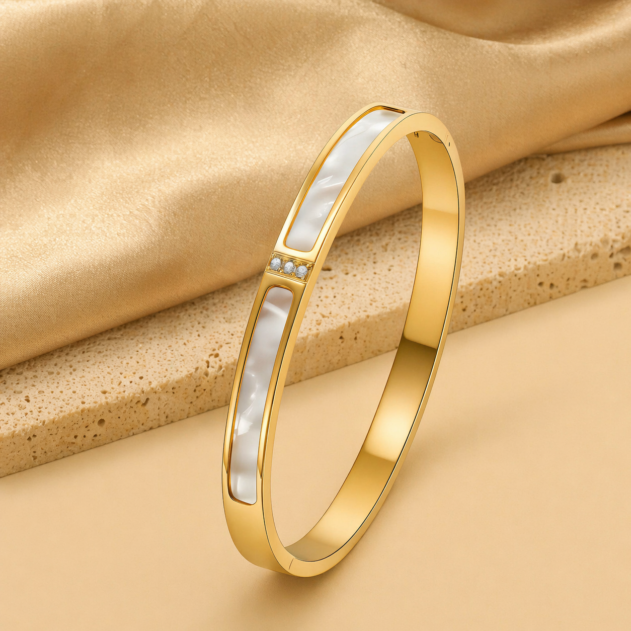 Gold bracelet with a white inlay on a beige fabric background