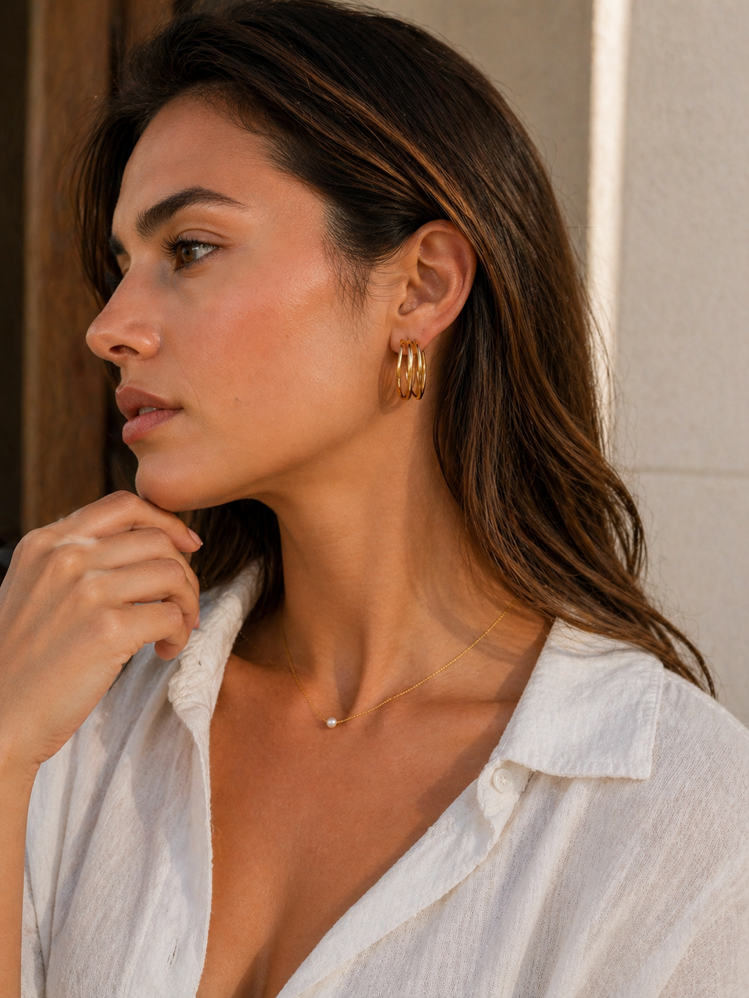 Woman wearing gold hoop earrings and a white blouse.
