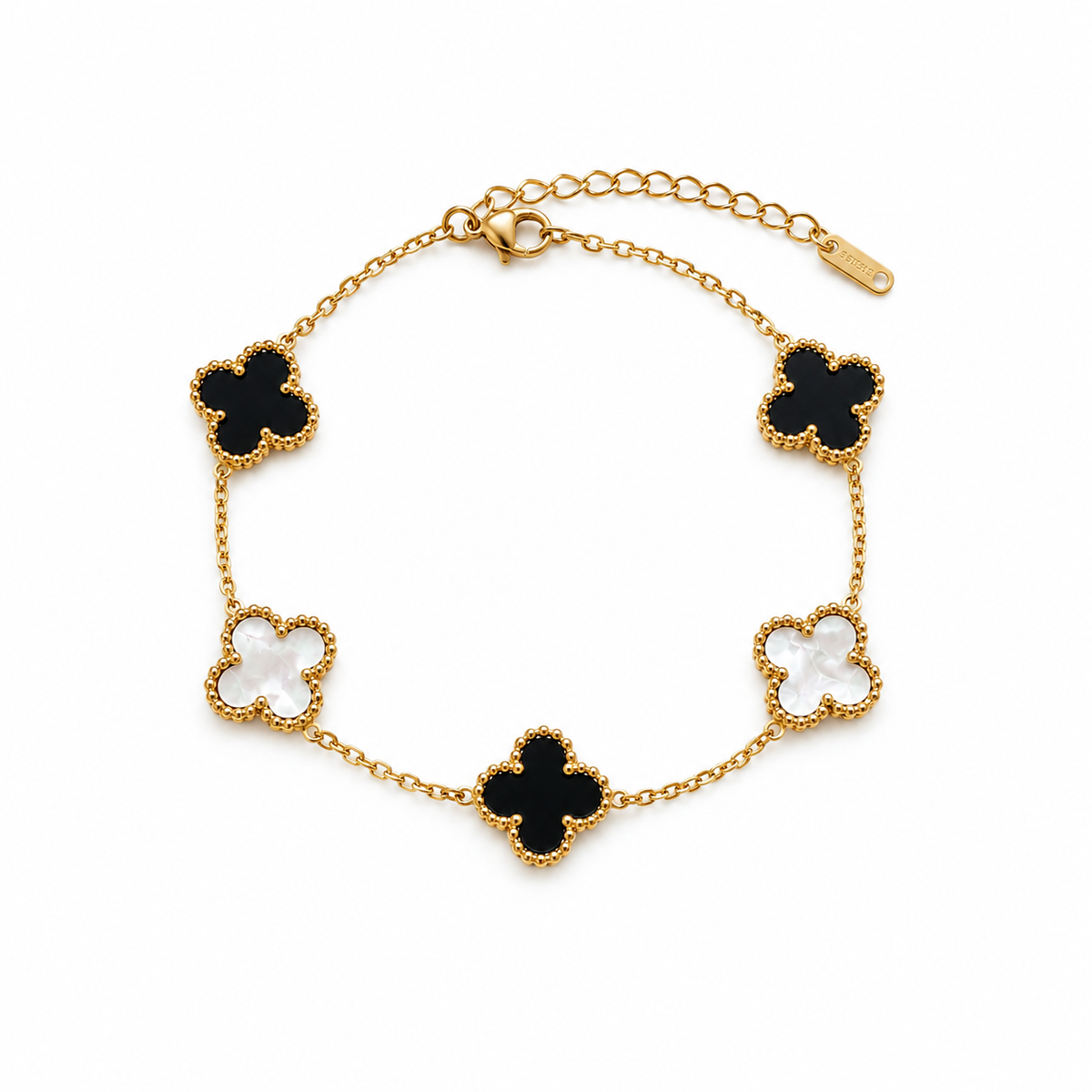 A gold chain bracelet with five clover-shaped motifs, alternating between black enamel and white enamel, set against a plain white background.