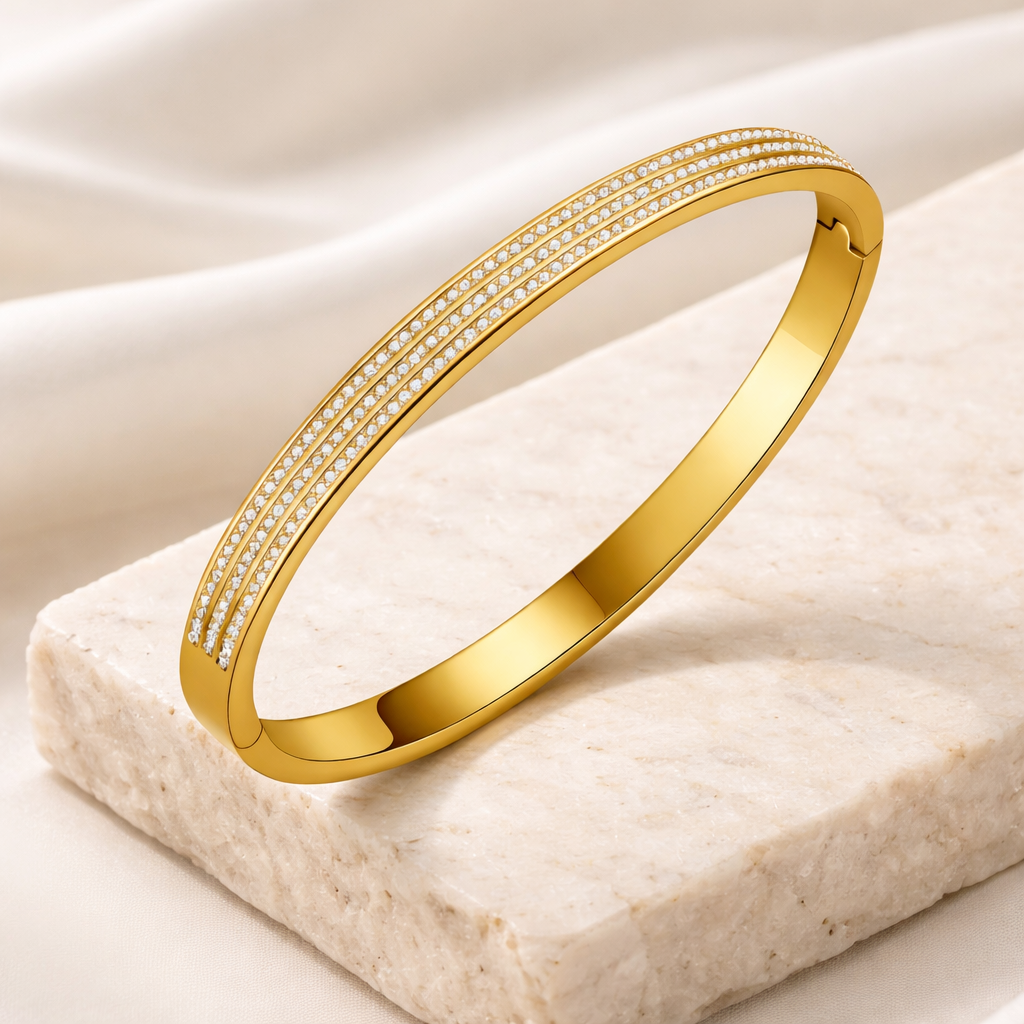 Gold bracelet with embedded stones on a beige stone surface
