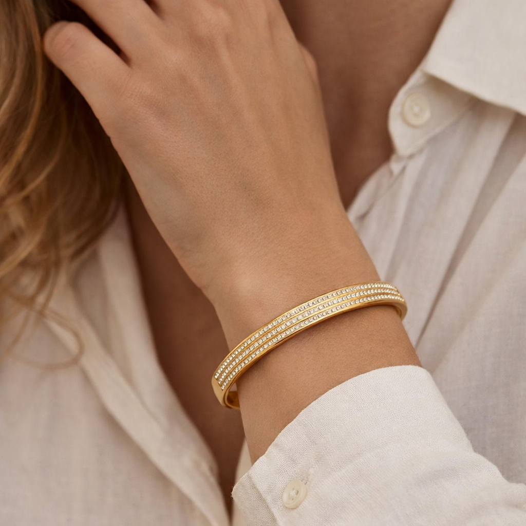 Gold bracelet on a wrist with a neutral background