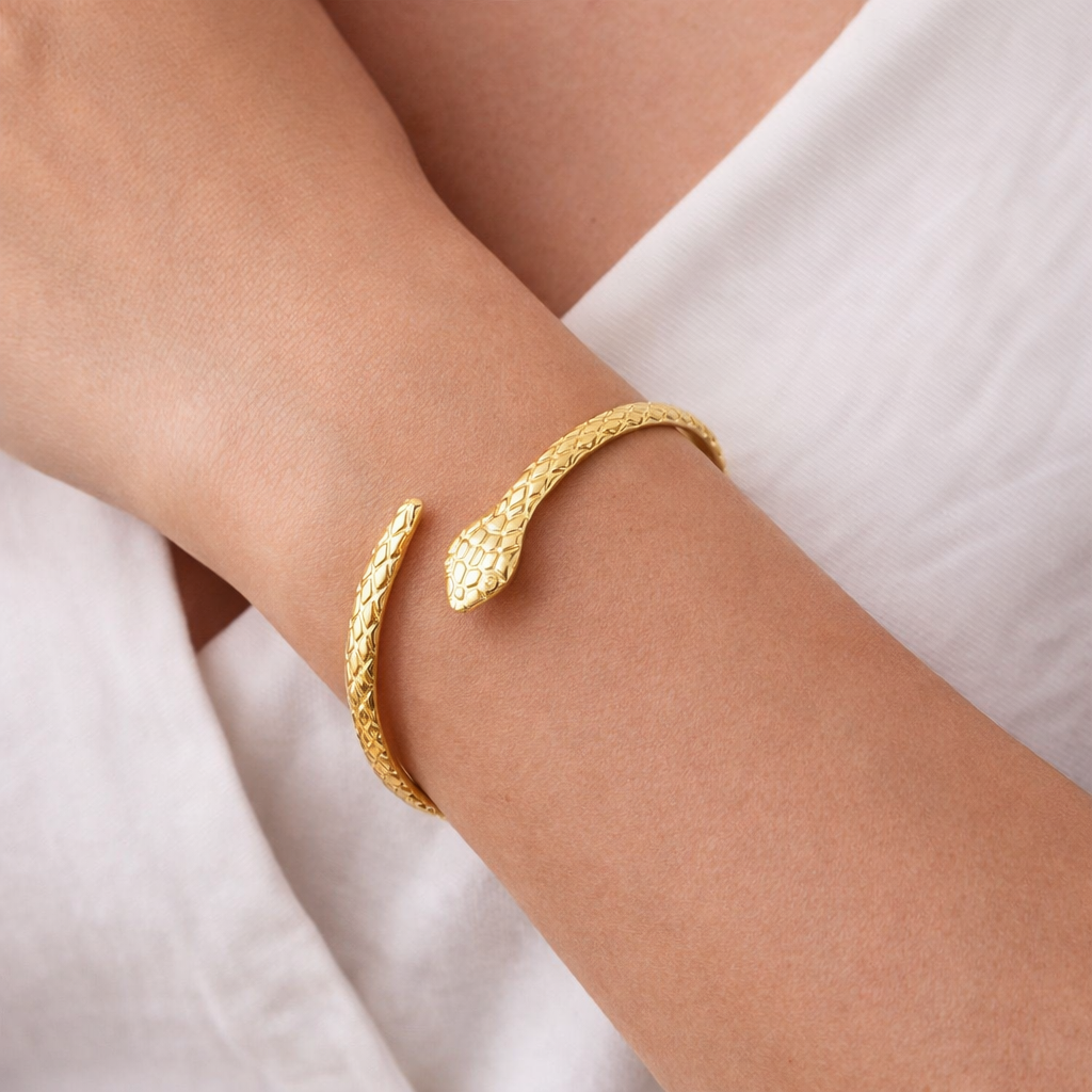 Gold bracelet on a person's wrist with a white fabric background