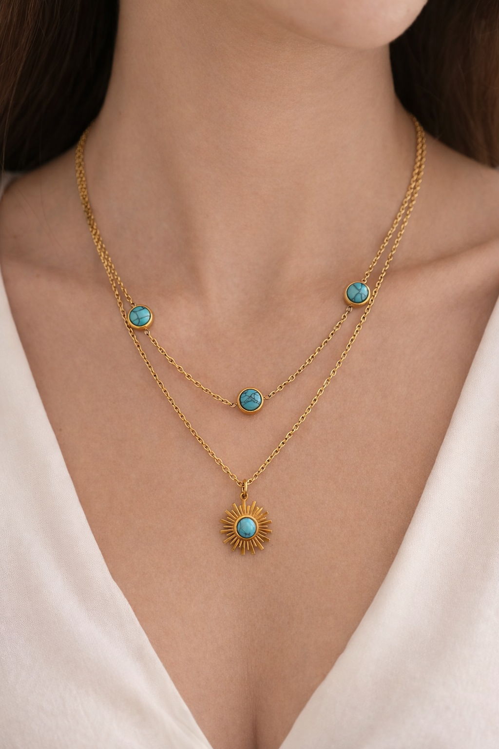 Gold necklace with turquoise stones worn by a model against a neutral background