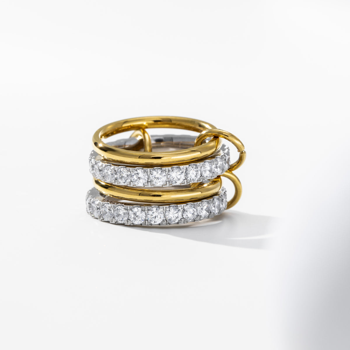 A luxury gold ring with three stacked bands: two smooth polished gold bands and one pavé-set diamond band, photographed on a clean white background.