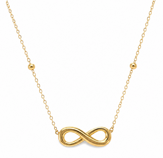 A gold necklace featuring a polished infinity symbol pendant at the center, suspended from a delicate gold chain with small gold bead accents on either side, set against a plain white background.