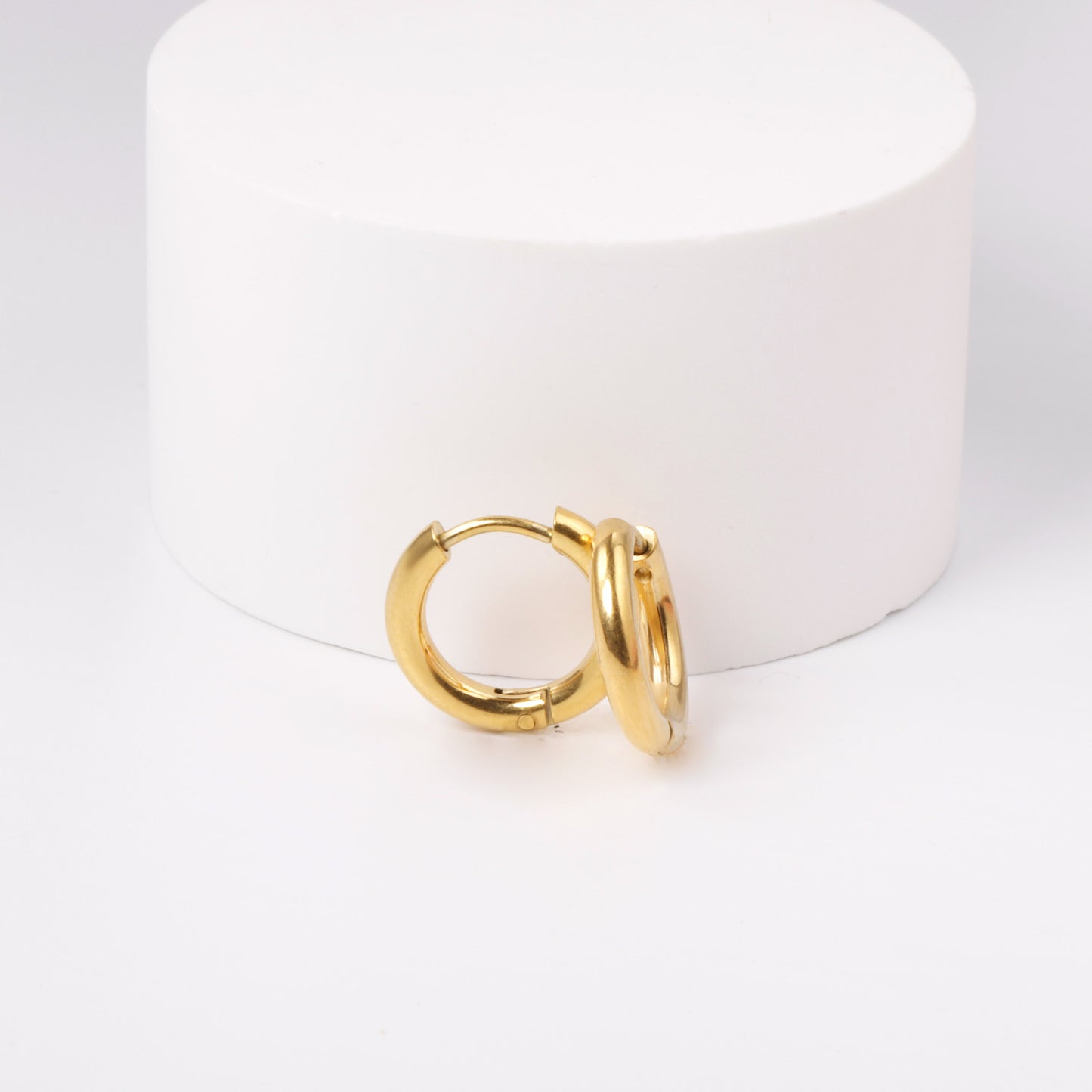 Gold hoop earrings on a white cylindrical object
