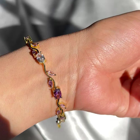 Gold bracelet with multicolored gemstones on a beige background