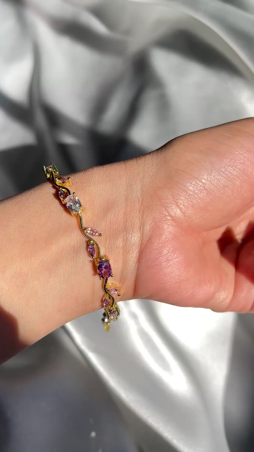 Gold bracelet with multicolored gemstones on a beige background